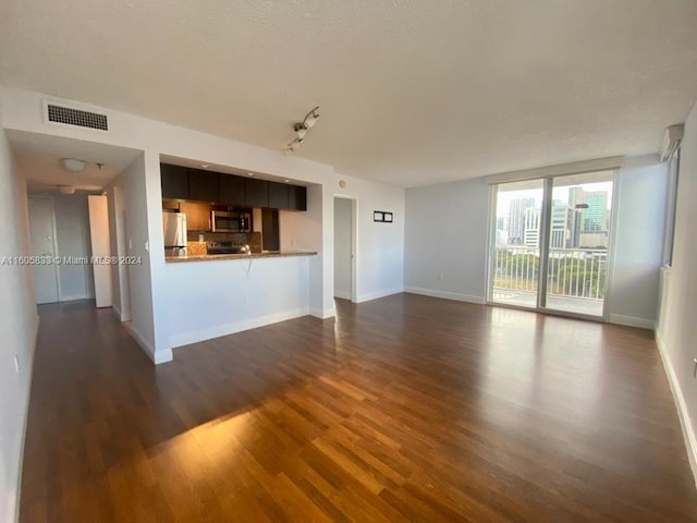 unfurnished living room featuring dark wood-type flooring and track lighting