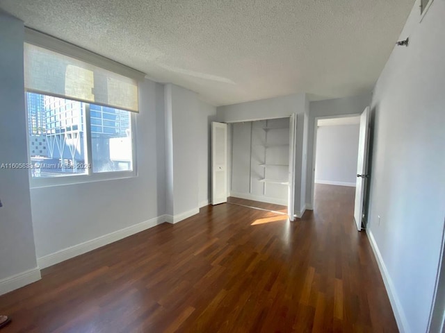 unfurnished bedroom featuring a closet, a textured ceiling, and dark hardwood / wood-style floors