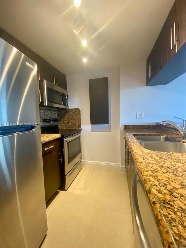 kitchen with tasteful backsplash, light tile patterned floors, stainless steel appliances, light stone countertops, and sink