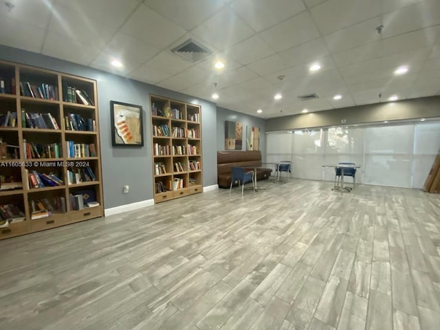 unfurnished living room featuring wood-type flooring and a drop ceiling