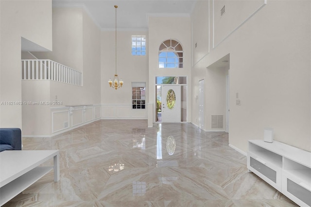 foyer entrance with a notable chandelier, light tile patterned flooring, crown molding, and a towering ceiling