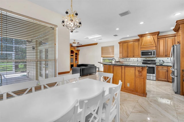 kitchen with plenty of natural light, decorative backsplash, a kitchen island with sink, and stainless steel appliances