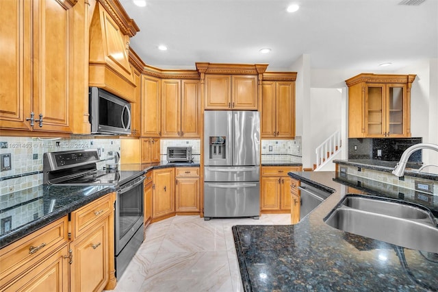 kitchen featuring tasteful backsplash, light tile patterned floors, dark stone counters, appliances with stainless steel finishes, and sink