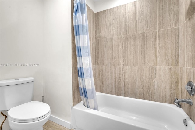 bathroom featuring toilet and shower / tub combo with curtain