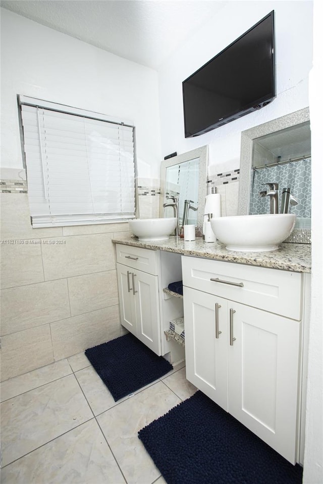 bathroom with tile patterned floors, double sink vanity, and tile walls