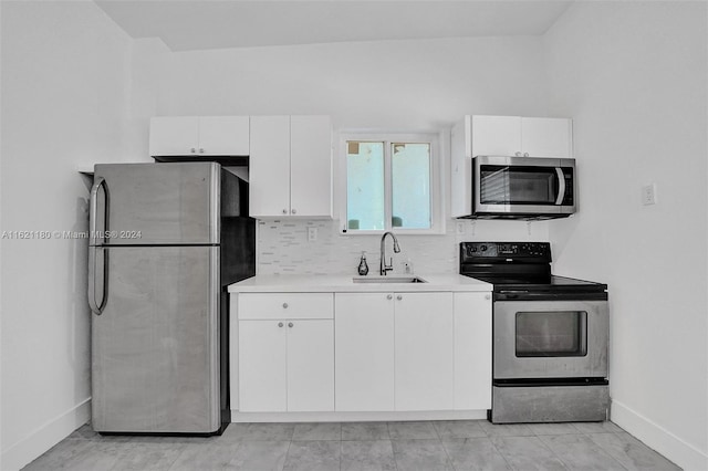 kitchen featuring sink, stainless steel appliances, light tile patterned floors, and white cabinets