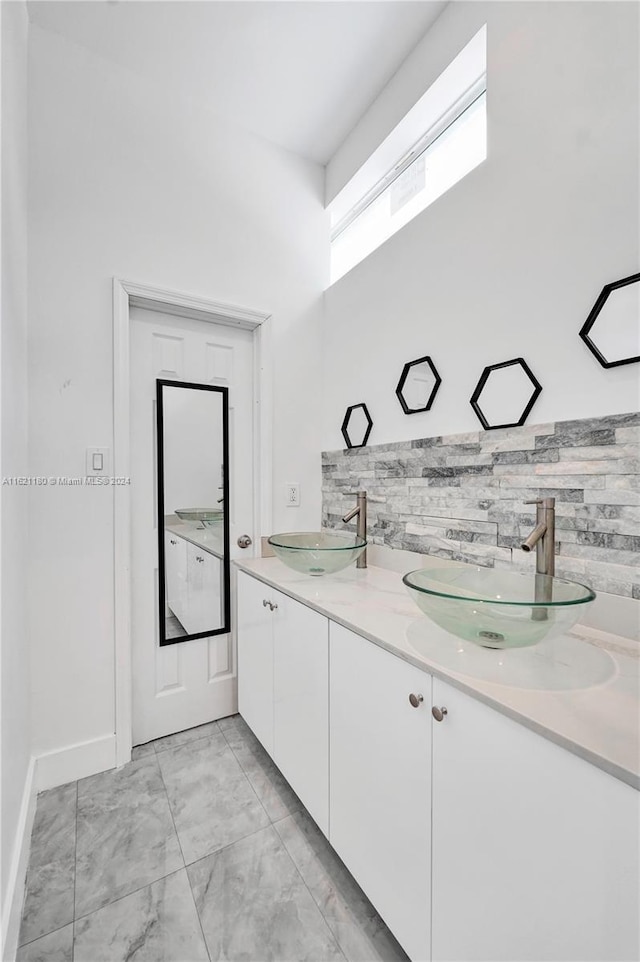 bathroom featuring tile patterned floors, tasteful backsplash, and dual bowl vanity