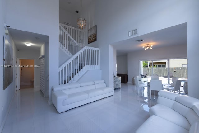 tiled living room featuring a notable chandelier and a towering ceiling