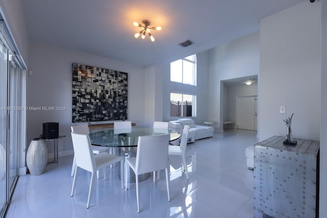 dining area featuring light tile patterned floors and a towering ceiling