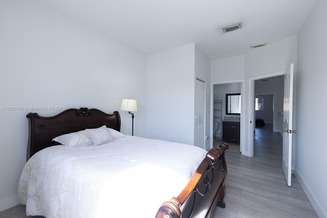 bedroom featuring ensuite bath, a closet, and light hardwood / wood-style floors