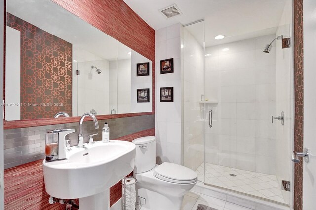 bathroom featuring sink, backsplash, an enclosed shower, toilet, and tile walls