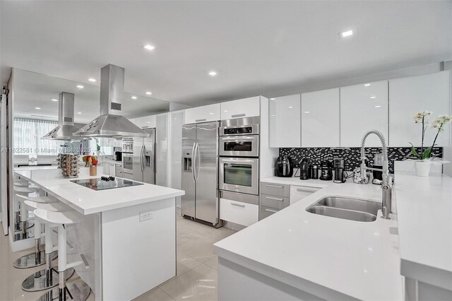 kitchen with island exhaust hood, appliances with stainless steel finishes, white cabinets, and exhaust hood