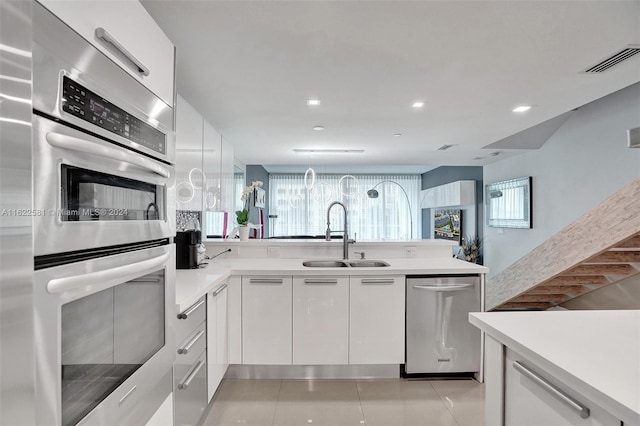 kitchen featuring light tile patterned floors, stainless steel appliances, white cabinetry, and sink