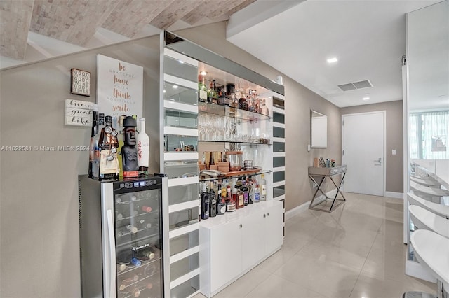 bar featuring wine cooler and light tile patterned floors