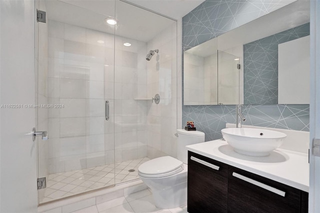 bathroom with a shower with door, vanity, tile walls, and toilet