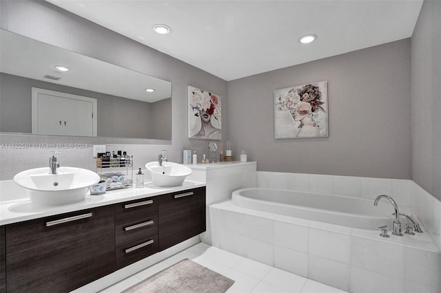 bathroom featuring backsplash, tiled bath, tile patterned flooring, and vanity