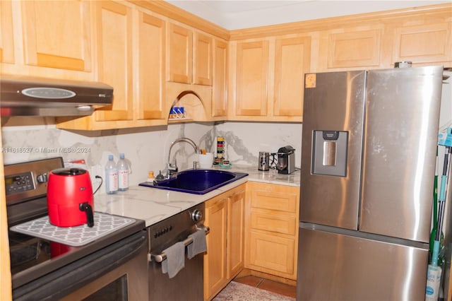 kitchen with appliances with stainless steel finishes, backsplash, light brown cabinetry, light stone counters, and sink