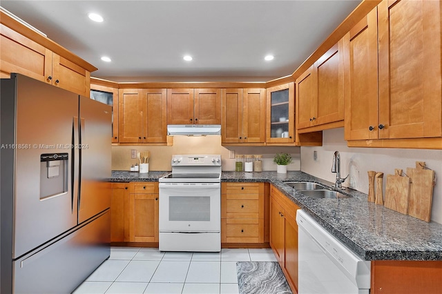 kitchen with light tile patterned floors, dark stone counters, sink, and white appliances