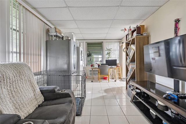 kitchen with a paneled ceiling, light tile patterned floors, and stainless steel fridge