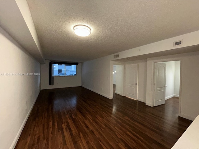 unfurnished room with dark wood-type flooring and a textured ceiling