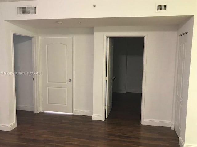 hall with visible vents, baseboards, and dark wood-style floors