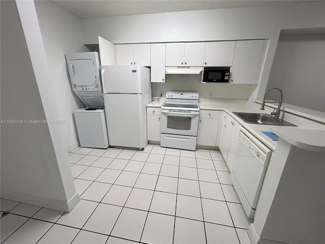 kitchen featuring under cabinet range hood, light countertops, stacked washing maching and dryer, white appliances, and a sink