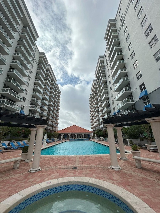 community pool with a hot tub and a patio