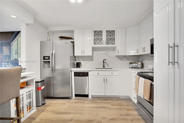 kitchen with white cabinetry, tasteful backsplash, stainless steel appliances, sink, and light hardwood / wood-style flooring