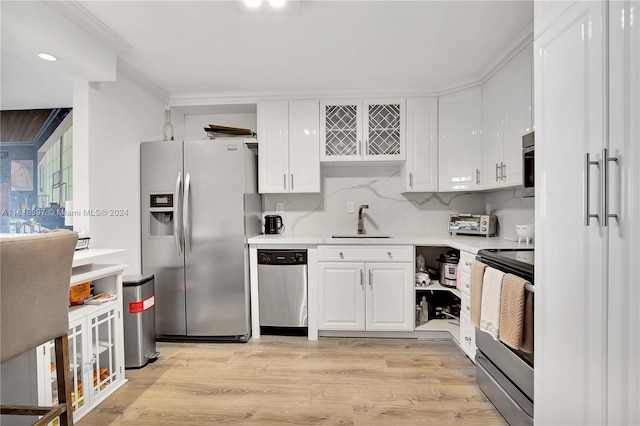 kitchen with stainless steel appliances, sink, backsplash, light wood-type flooring, and white cabinetry