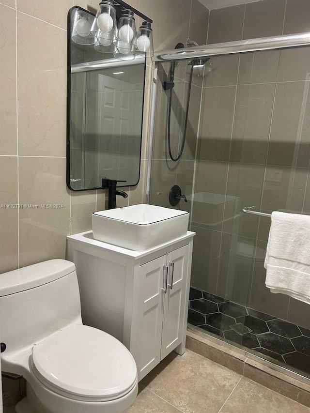 bathroom featuring a shower with door, vanity, tile walls, and toilet