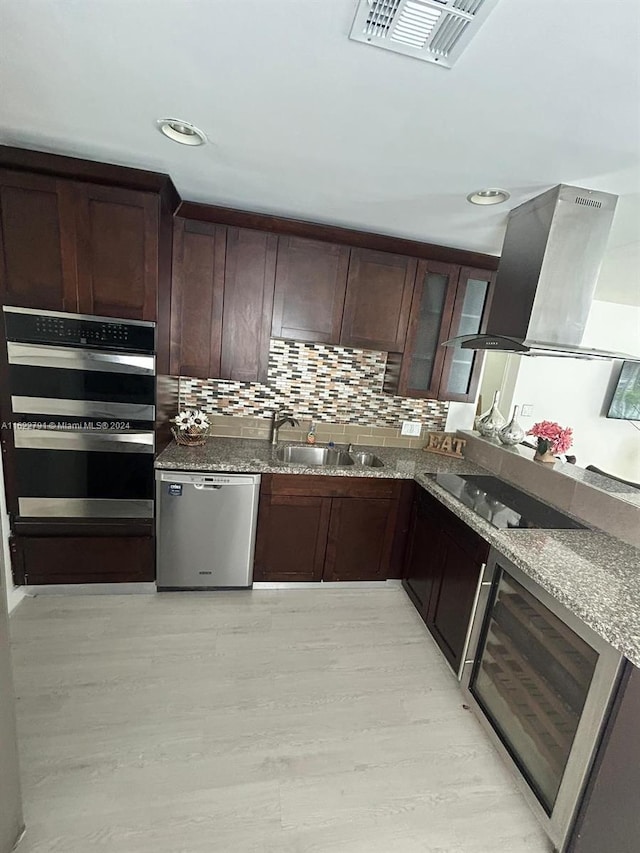 kitchen with stone counters, sink, light wood-type flooring, appliances with stainless steel finishes, and island exhaust hood