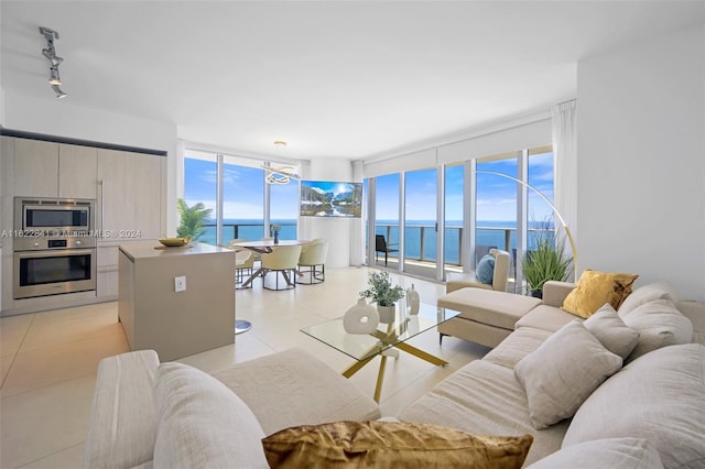 tiled living room with a wealth of natural light, a water view, and rail lighting