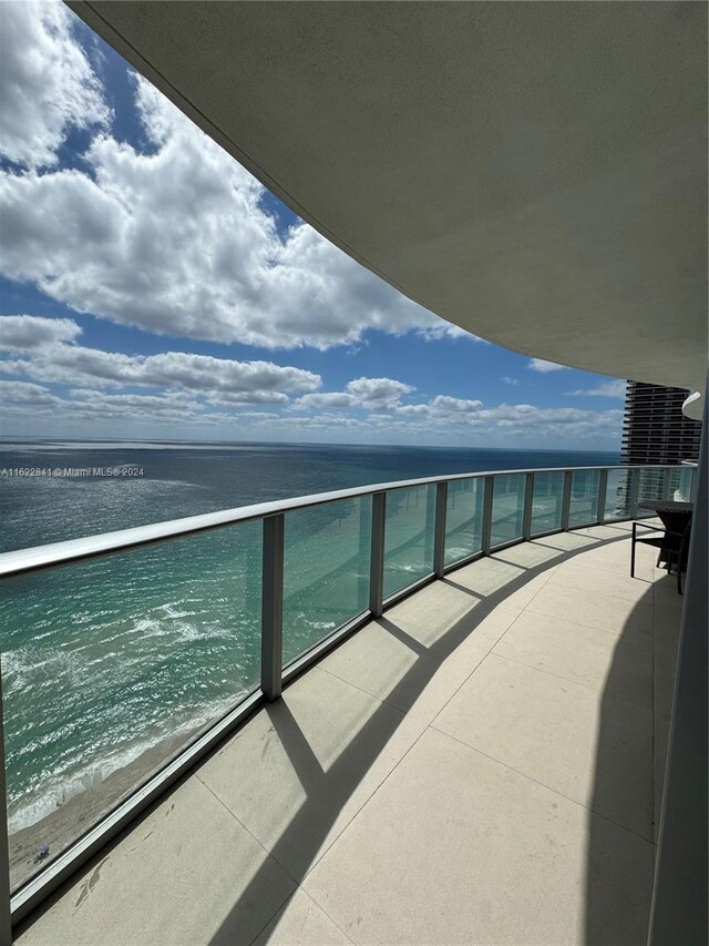 balcony featuring a water view and a beach view