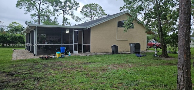 rear view of house with a sunroom and a lawn