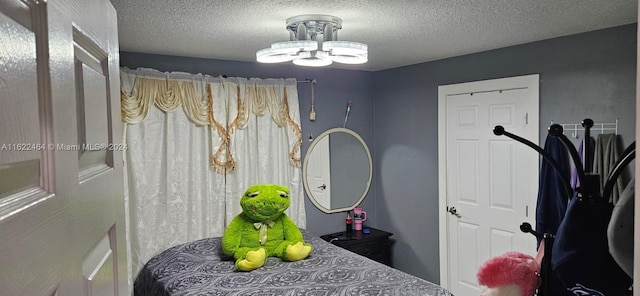 bedroom with an inviting chandelier and a textured ceiling