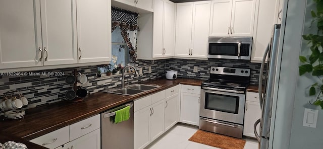 kitchen featuring decorative backsplash, butcher block countertops, appliances with stainless steel finishes, and sink