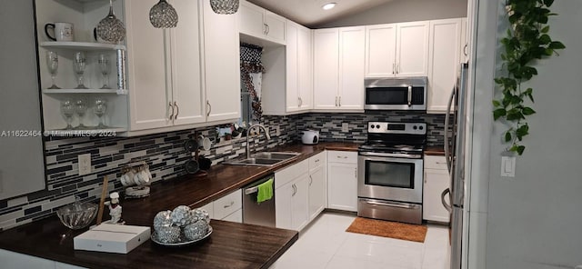 kitchen featuring tasteful backsplash, lofted ceiling, appliances with stainless steel finishes, and sink