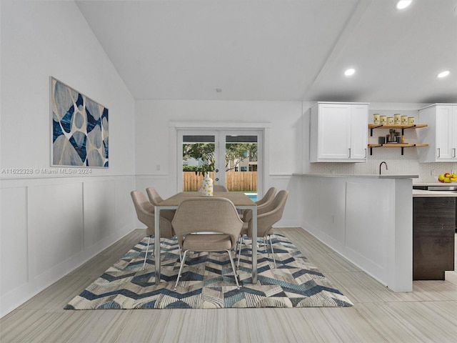 dining room with light hardwood / wood-style floors, french doors, sink, and vaulted ceiling