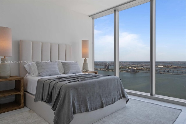 bedroom featuring a water view and a wall of windows