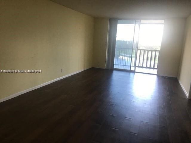 empty room featuring a wall of windows and dark hardwood / wood-style flooring