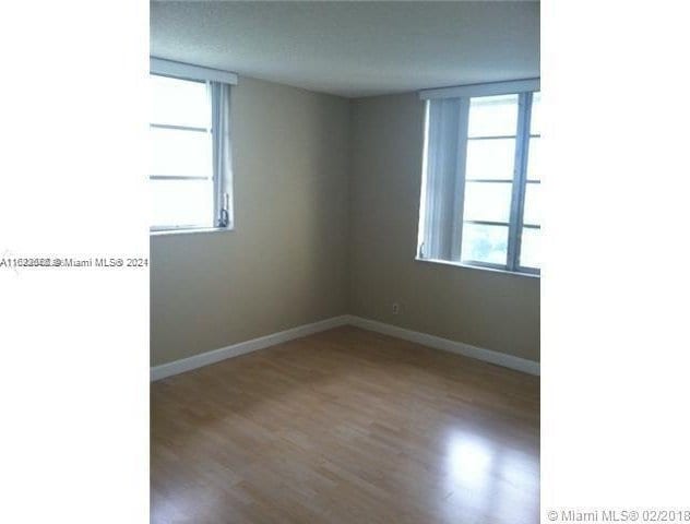 unfurnished room with hardwood / wood-style floors and a healthy amount of sunlight