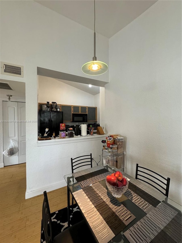 dining room with lofted ceiling and light hardwood / wood-style floors