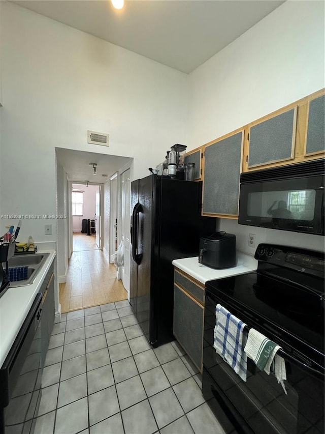 kitchen featuring light tile patterned flooring, sink, and black appliances