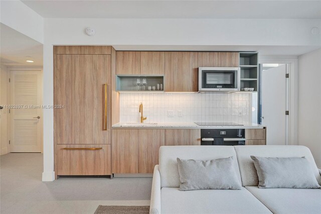 kitchen featuring sink, decorative backsplash, and black appliances