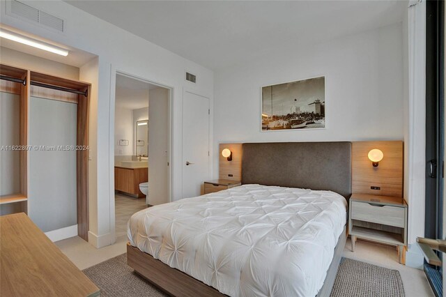 bedroom featuring ensuite bath, sink, a closet, and light colored carpet