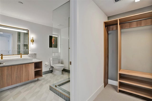 bathroom with tile patterned flooring, walk in shower, toilet, and vanity