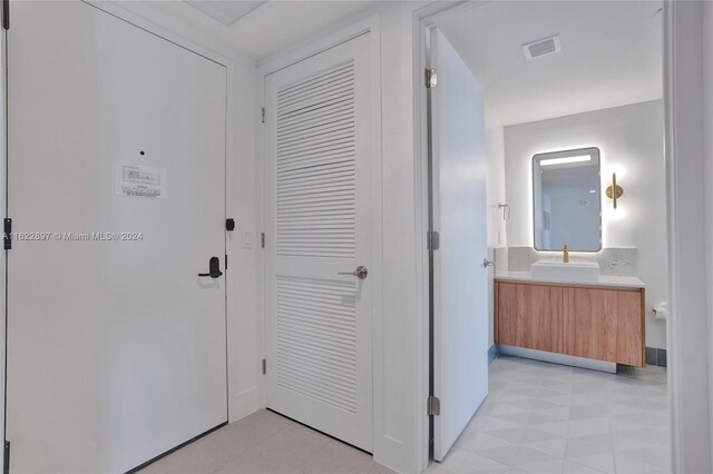 corridor featuring light tile patterned flooring and sink