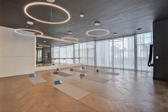 workout area with parquet floors, a wealth of natural light, and expansive windows