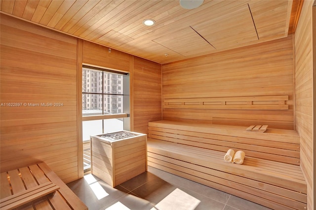 view of sauna with tile patterned flooring, wood walls, and wooden ceiling