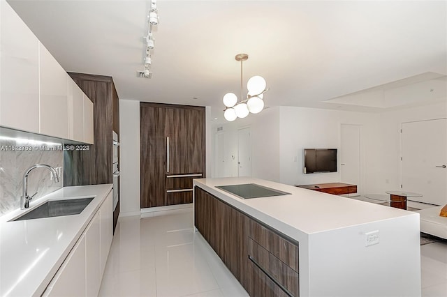 kitchen with a center island, white cabinets, sink, rail lighting, and decorative light fixtures